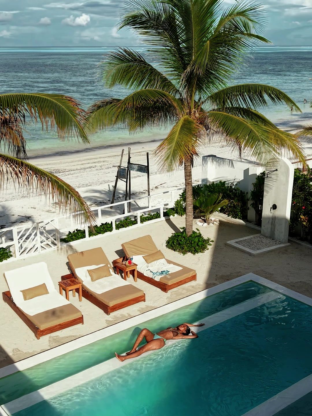 Private pool with sun loungers, palms and the ocean behind